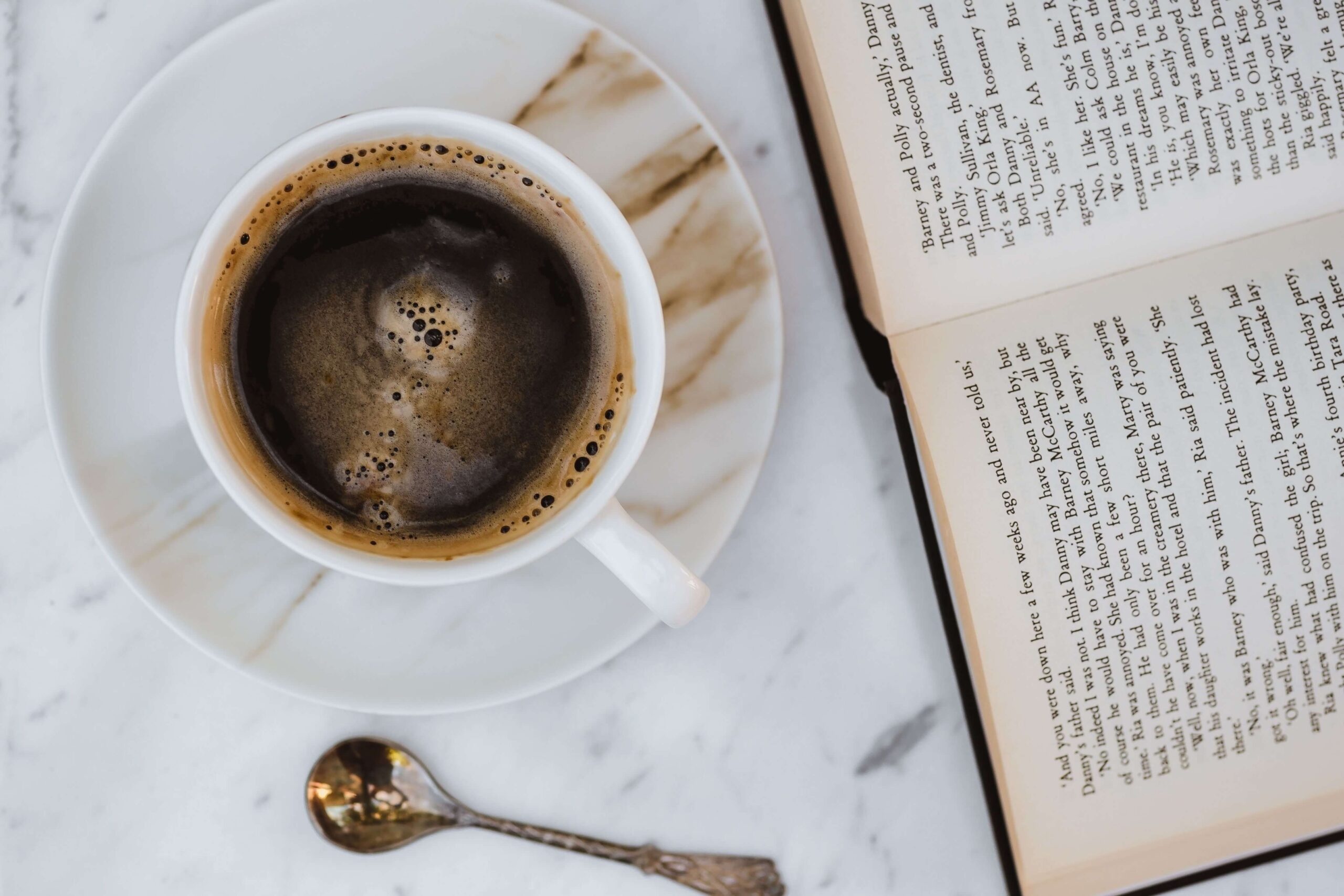 coffee cup sitting on marble stable next to open book